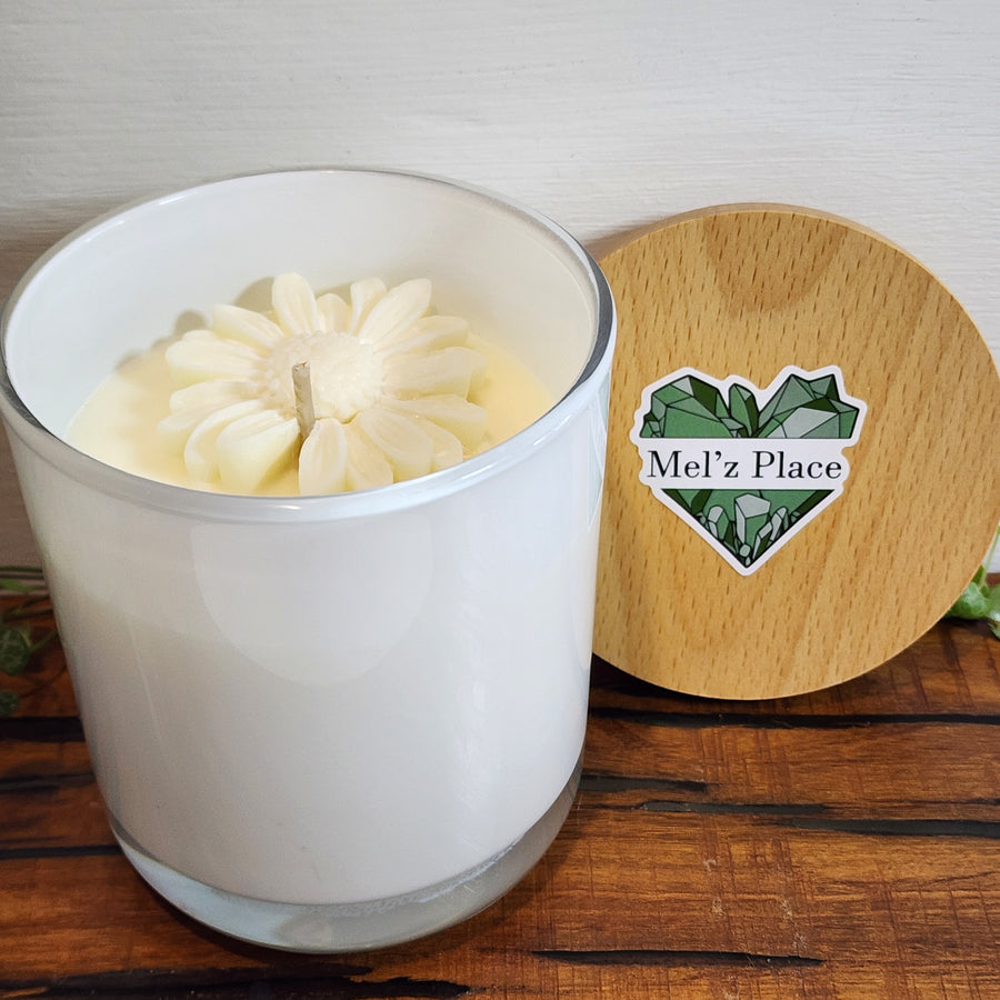 A large white soy candle in a clear container with a wooden lid, featuring a coconut and lime scent, handmade with a flower detail.